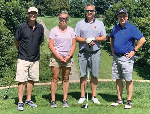 Four people standing outdoors with golfing equipment