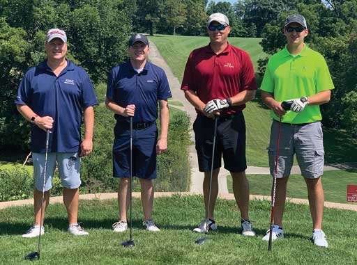 Four people standing outdoors with golfing equipment