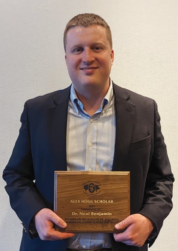 Neal Benjamin holding scholarship plaque