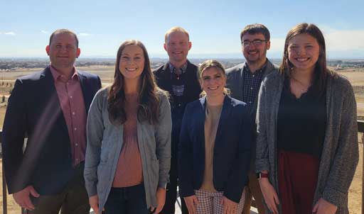 Six people standing outdoors facing the camera