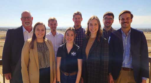 Eight people in two rows facing the camera outdoors