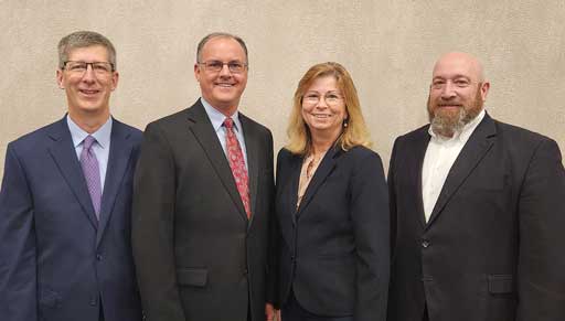 Four people standing in a row facing the camera