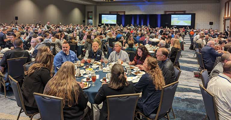 People eating at numerous round tables in a hotel ballroom